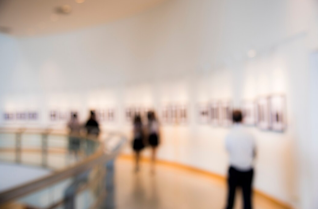 a blurred photo of people  standing near pictures on the wall in the gallery