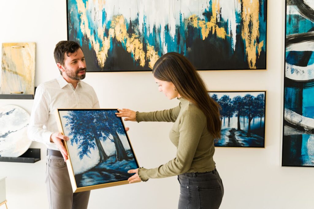 Male artist showing his painting to a female client interested in buying it