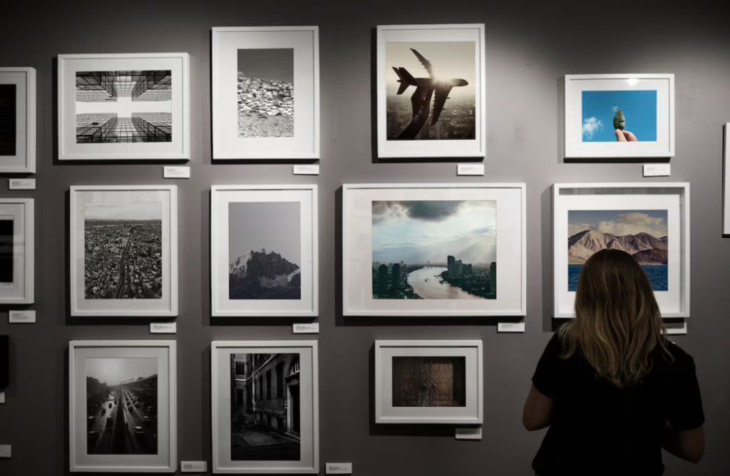 woman in black t-shirt standing near the wall with pictures of landscapes and airplane
